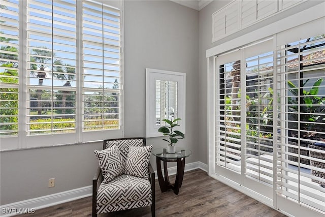 living area featuring dark wood-style flooring, baseboards, and crown molding