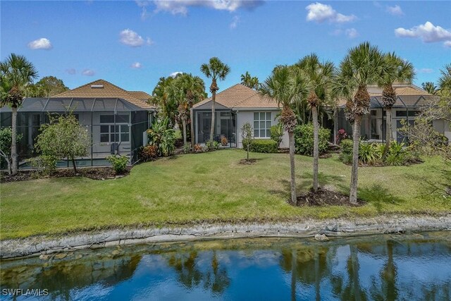 rear view of property with a water view, a lawn, and glass enclosure