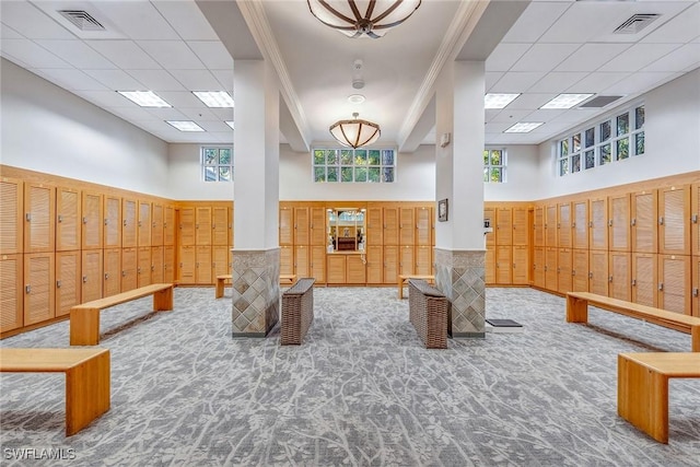 building lobby featuring a towering ceiling, a drop ceiling, and wainscoting