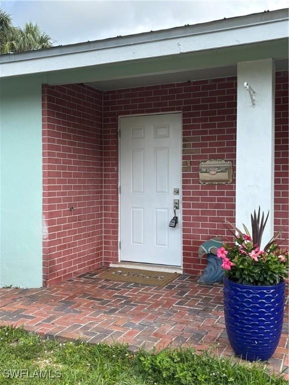 view of exterior entry featuring brick siding