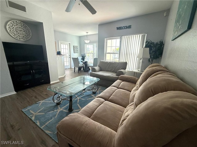 living room with wood finished floors, a ceiling fan, visible vents, baseboards, and a textured wall