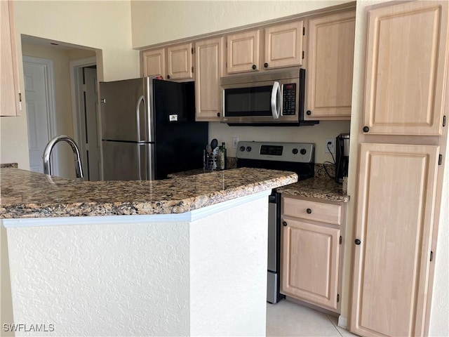 kitchen with a sink, a peninsula, stainless steel appliances, and light brown cabinetry