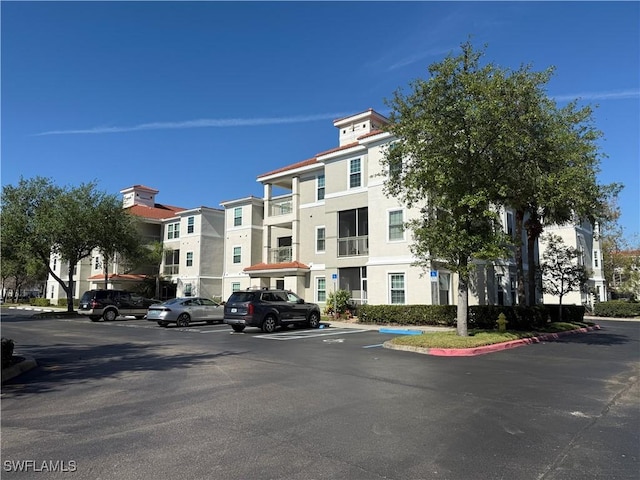 view of building exterior with uncovered parking and a residential view