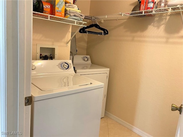washroom featuring laundry area, washer and clothes dryer, baseboards, and light tile patterned flooring