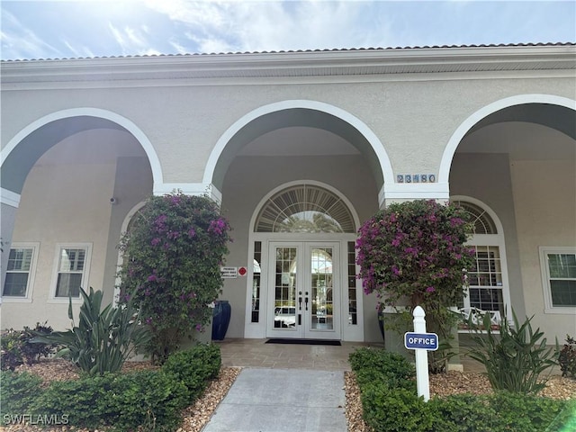 view of exterior entry featuring stucco siding and french doors