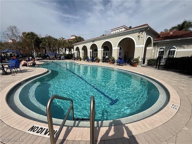 community pool with a patio and fence