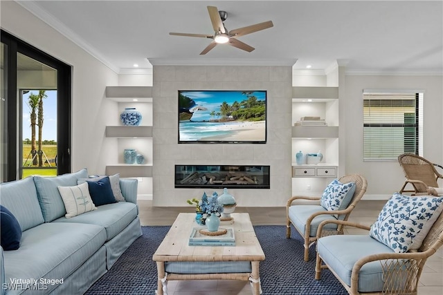 19402 Hinkley Dr, Estero, FL 33928 - living room featuring built in features, ornamental molding, plenty of natural light, a tiled fireplace, and ceiling fan