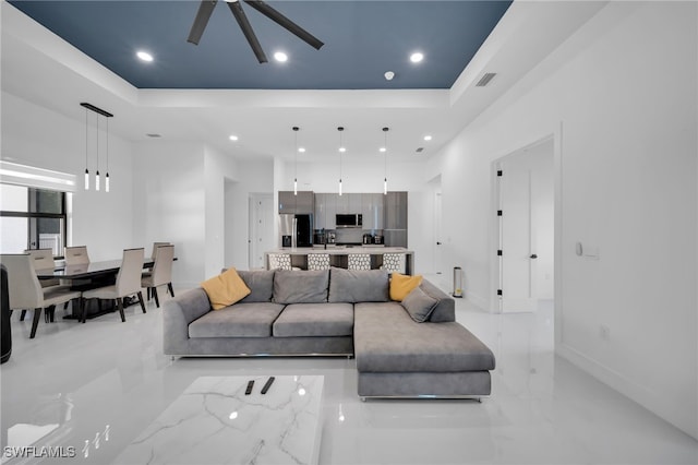living area featuring a tray ceiling, visible vents, and recessed lighting