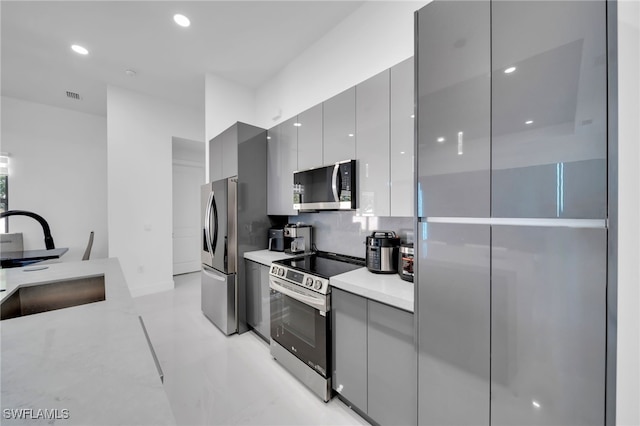 kitchen with modern cabinets, a sink, appliances with stainless steel finishes, and gray cabinets