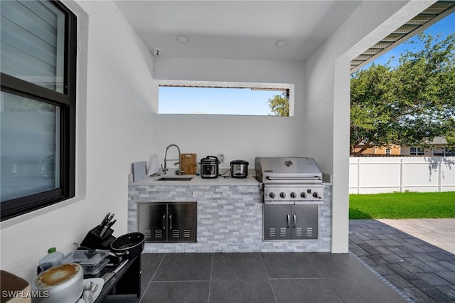 view of patio featuring a sink, grilling area, fence, and an outdoor kitchen