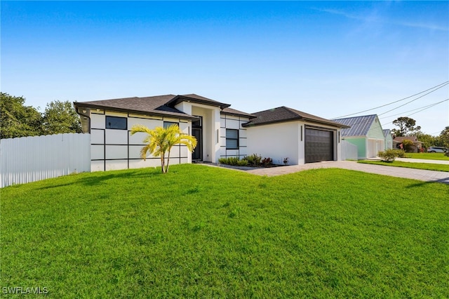 prairie-style home with a garage, driveway, fence, and a front yard