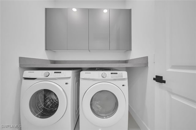 clothes washing area featuring cabinet space and independent washer and dryer