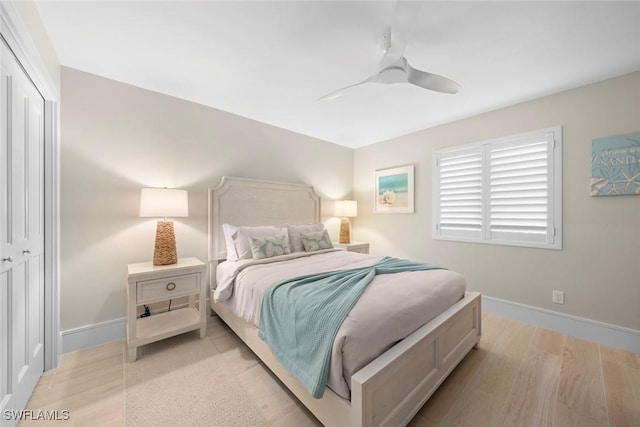bedroom featuring baseboards, light wood-style floors, a closet, and ceiling fan
