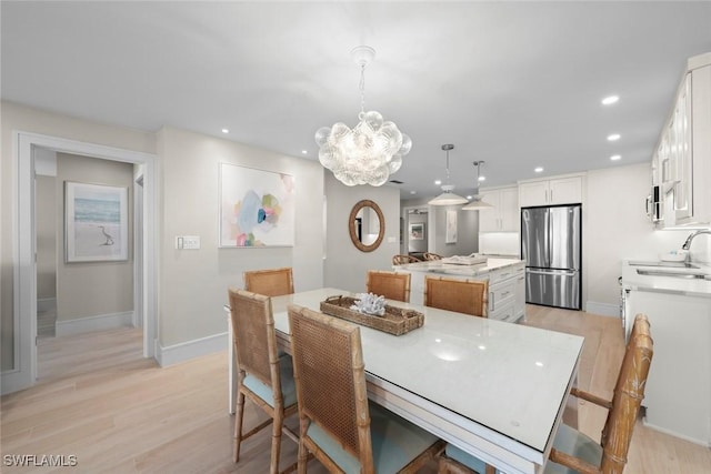 dining space featuring light wood-style floors, a chandelier, baseboards, and recessed lighting