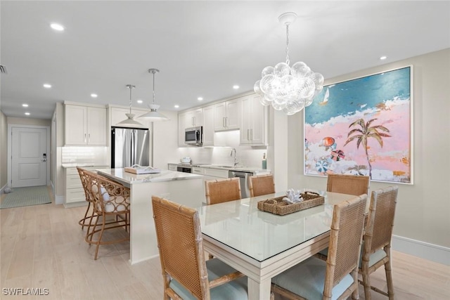 dining space with light wood-style floors, an inviting chandelier, and recessed lighting