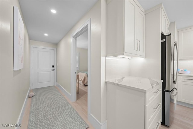hall with light wood finished floors, baseboards, and recessed lighting