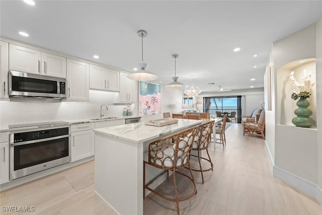 kitchen featuring a sink, stainless steel appliances, a kitchen breakfast bar, white cabinetry, and a kitchen island