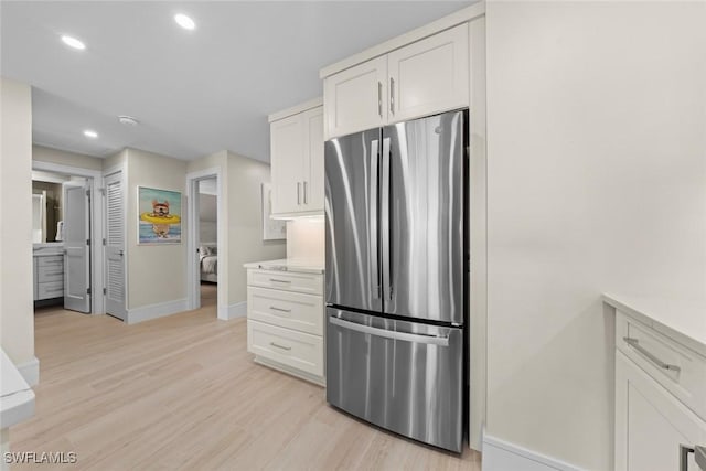 kitchen featuring freestanding refrigerator, baseboards, light wood finished floors, and white cabinetry