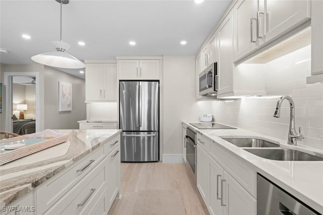 kitchen featuring light wood-style flooring, recessed lighting, a sink, stainless steel appliances, and white cabinets
