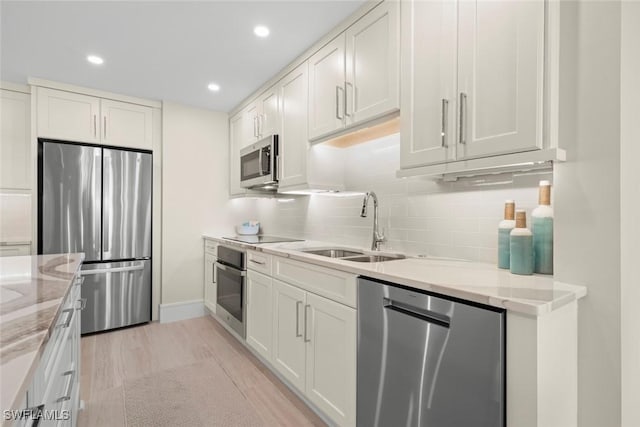 kitchen with light stone countertops, baseboards, a sink, decorative backsplash, and appliances with stainless steel finishes