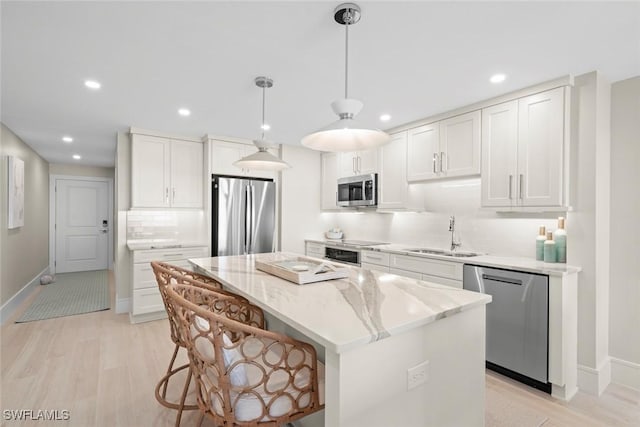 kitchen with recessed lighting, appliances with stainless steel finishes, a sink, and a kitchen island