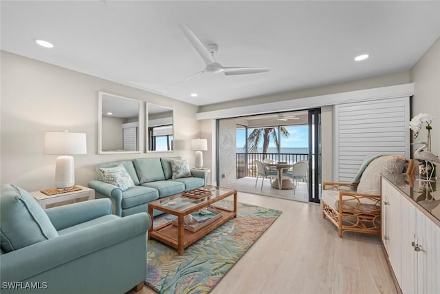 living room featuring a water view, light wood-style flooring, ceiling fan, and recessed lighting