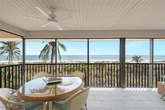 sunroom with a beach view, a water view, and a ceiling fan