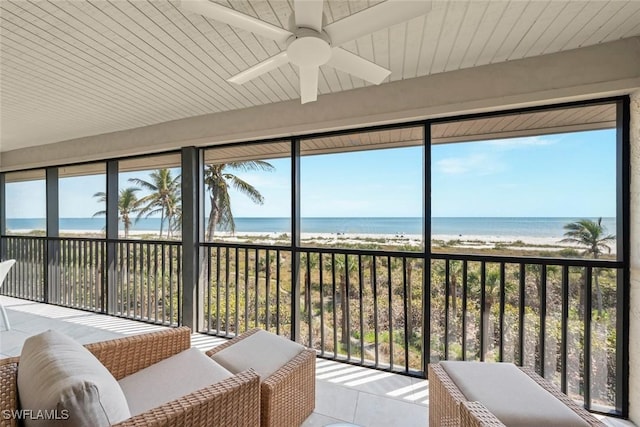 sunroom / solarium with a beach view and a ceiling fan