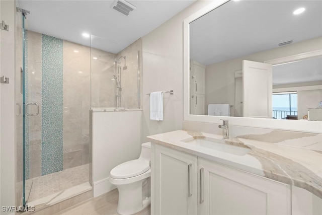 bathroom featuring vanity, toilet, a shower stall, and visible vents