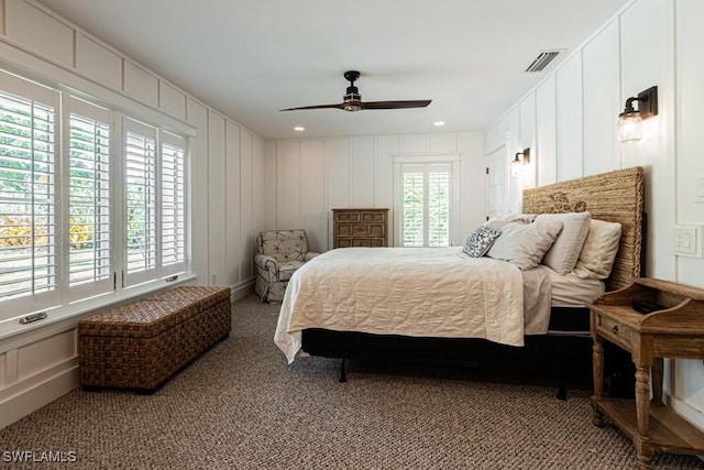 carpeted bedroom featuring a decorative wall and a ceiling fan