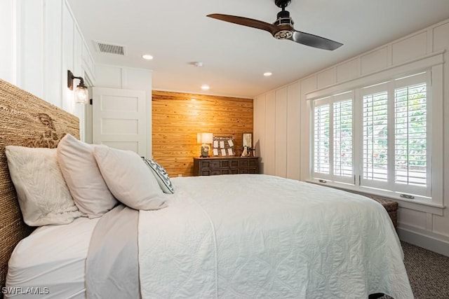 bedroom featuring carpet floors, a decorative wall, wooden walls, a ceiling fan, and recessed lighting