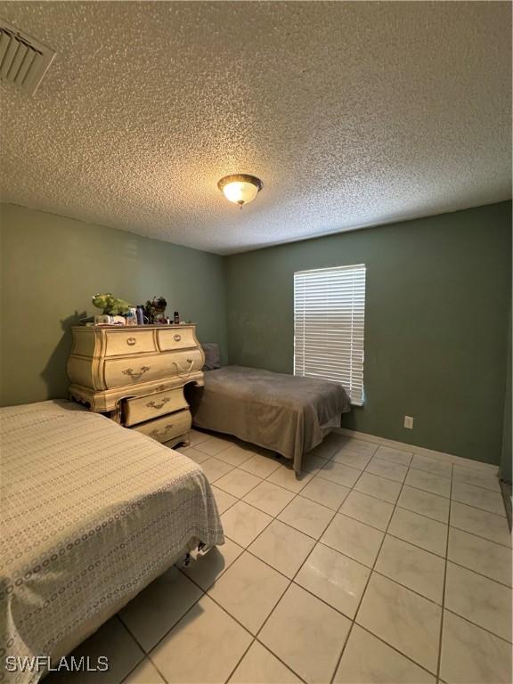 11688 Saunders Ave, Bonita Springs, FL 34135 - bedroom with light tile patterned floors, visible vents, and a textured ceiling