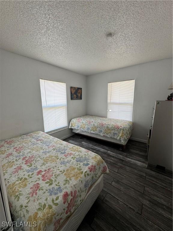 11688 Saunders Ave, Bonita Springs, FL 34135 - bedroom featuring a textured ceiling and dark wood-style floors