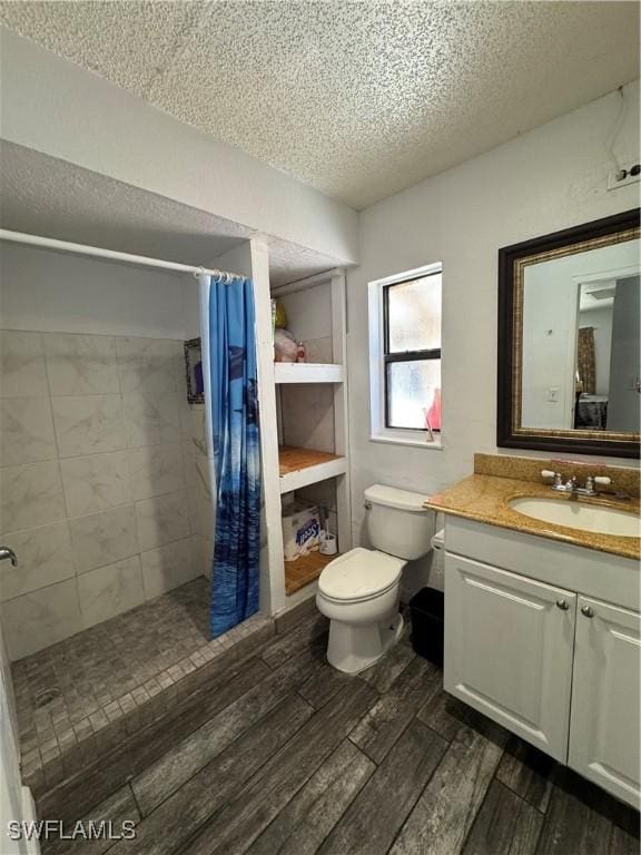 11688 Saunders Ave, Bonita Springs, FL 34135 - bathroom featuring toilet, wood finished floors, tiled shower, a textured ceiling, and vanity