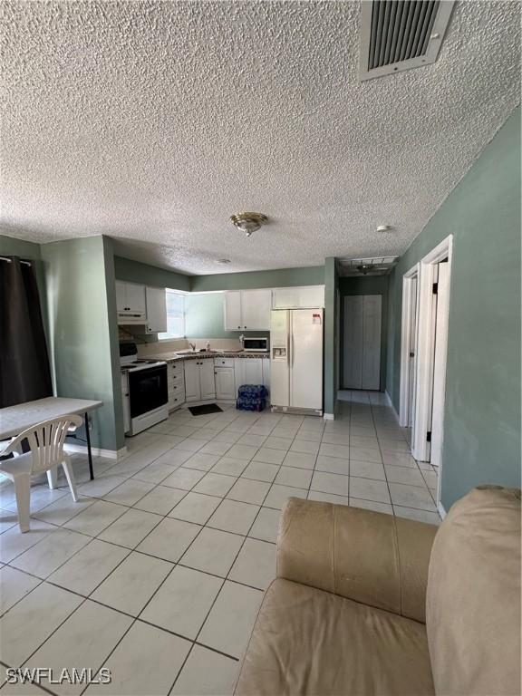 11688 Saunders Ave, Bonita Springs, FL 34135 - kitchen with white appliances, light tile patterned flooring, a textured ceiling, visible vents, and under cabinet range hood