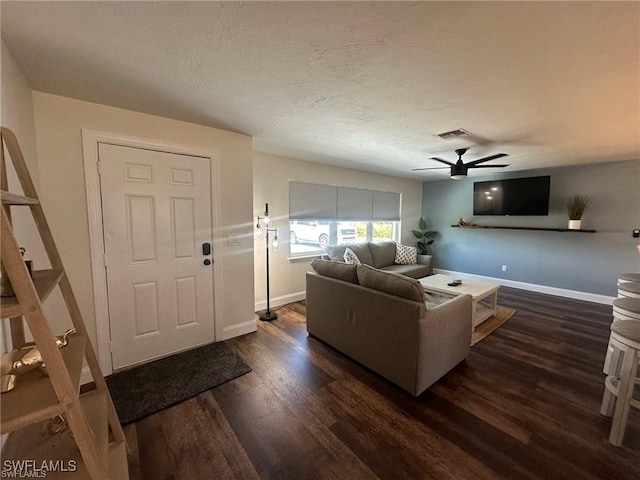 living room featuring dark wood finished floors, ceiling fan, baseboards, and a textured ceiling
