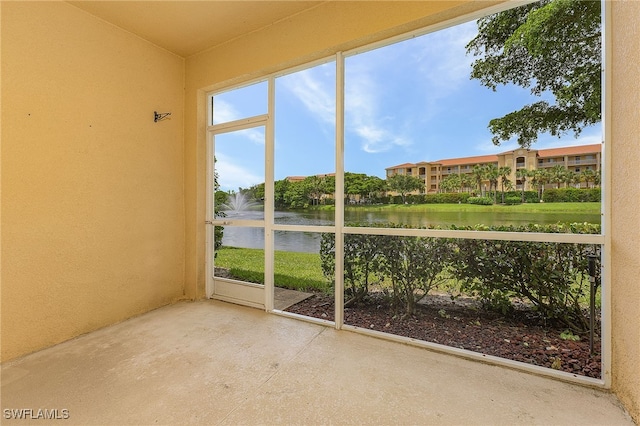 unfurnished sunroom featuring a water view and concrete flooring