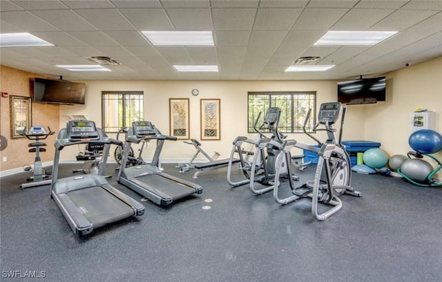 gym featuring a paneled ceiling and baseboards