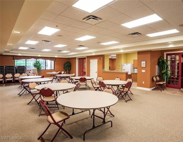 dining area with a drop ceiling and light colored carpet