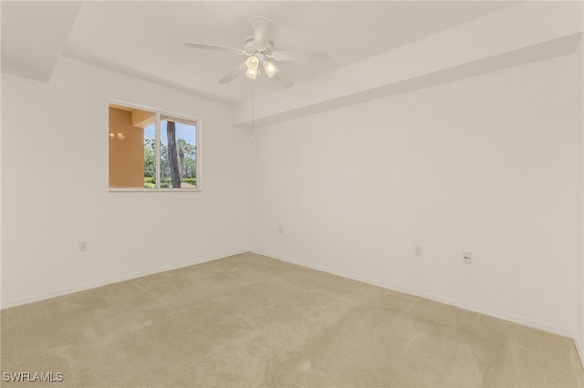 unfurnished room featuring light colored carpet, a ceiling fan, and baseboards
