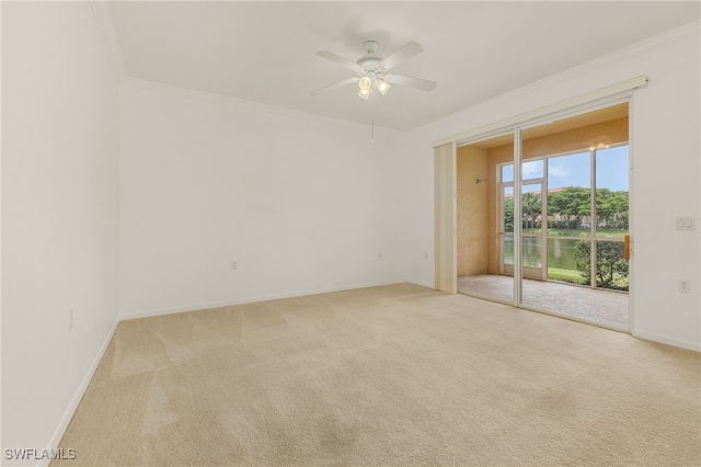 spare room with light carpet, ornamental molding, a ceiling fan, and baseboards