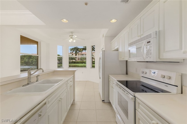 kitchen with white appliances, a sink, light tile patterned flooring, ceiling fan, and white cabinetry