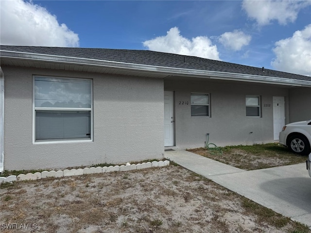 view of front facade featuring stucco siding and roof with shingles