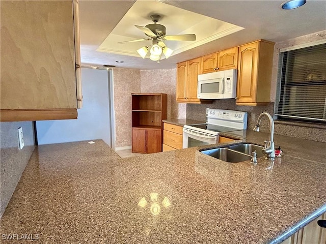 kitchen with white appliances, a tray ceiling, a sink, and ceiling fan
