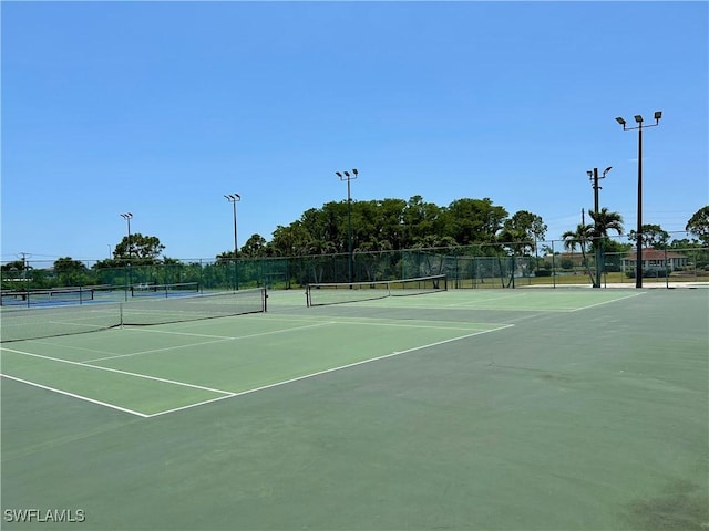 view of tennis court featuring fence and community basketball court