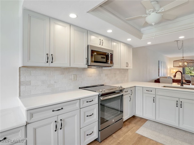 13111 Cross Creek Blvd Unit 208, Fort Myers, FL 33912 - kitchen with appliances with stainless steel finishes, a sink, a tray ceiling, light wood finished floors, and recessed lighting
