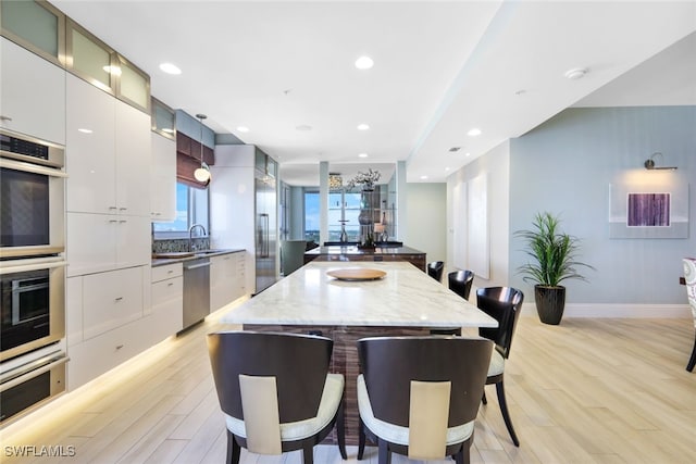 14220 Royal Harbour Ct Unit 607, Fort Myers, FL 33908 - kitchen featuring a kitchen breakfast bar, appliances with stainless steel finishes, modern cabinets, light wood-style floors, and a kitchen island