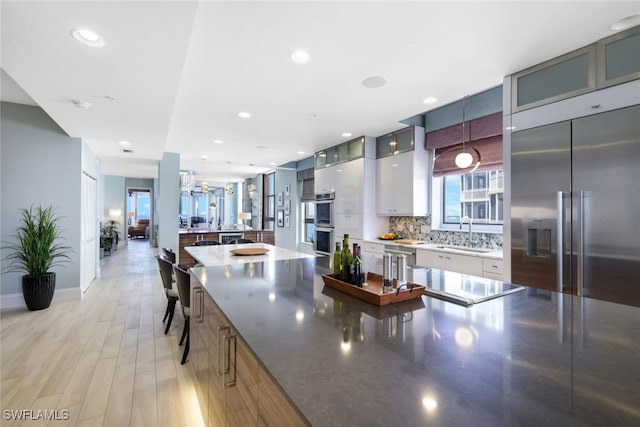 14220 Royal Harbour Ct Unit 607, Fort Myers, FL 33908 - kitchen featuring stainless steel appliances, glass insert cabinets, tasteful backsplash, light wood-style flooring, and pendant lighting