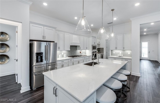 kitchen with a center island with sink, premium range hood, appliances with stainless steel finishes, and dark wood-type flooring