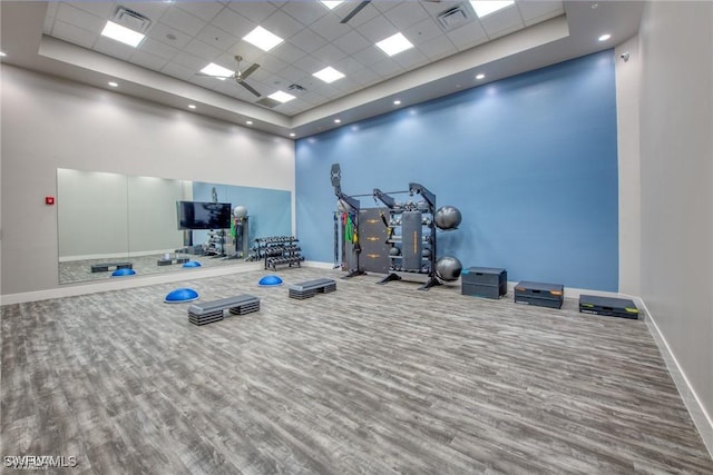 workout area with wood finished floors, visible vents, a drop ceiling, a high ceiling, and baseboards